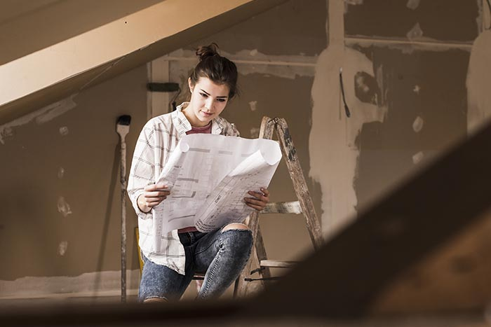 Woman holding construction plans while renovating a home