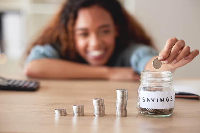 Woman stacking coins and adding them to a jar marked