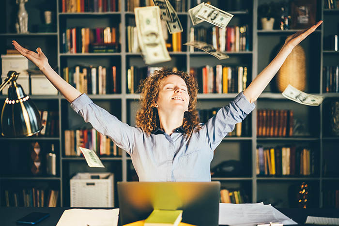 Woman in a home office throwing money into the air