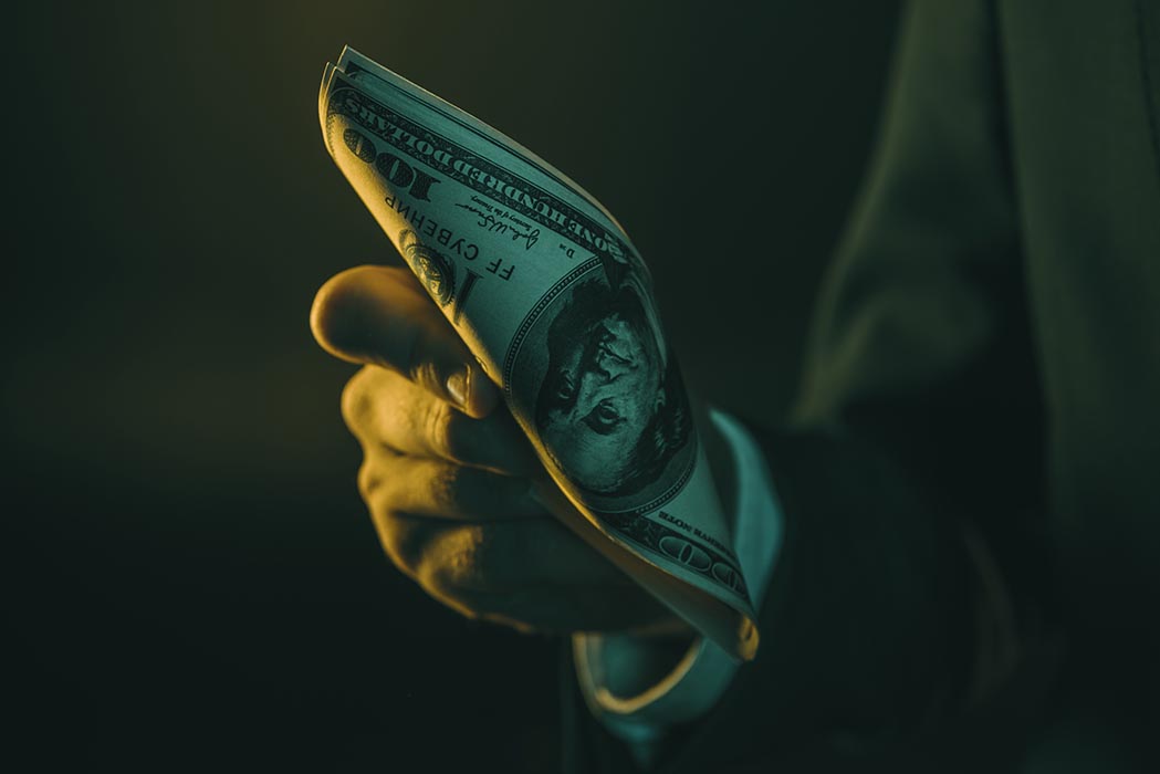 Person holding money with dark, mysterious lighting
