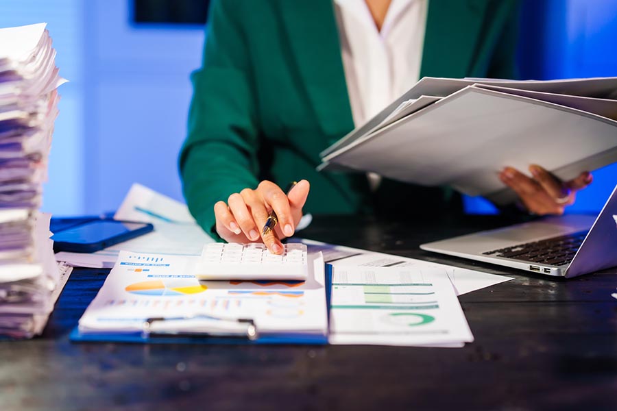 Person at a desk making calculations while doing paperwork