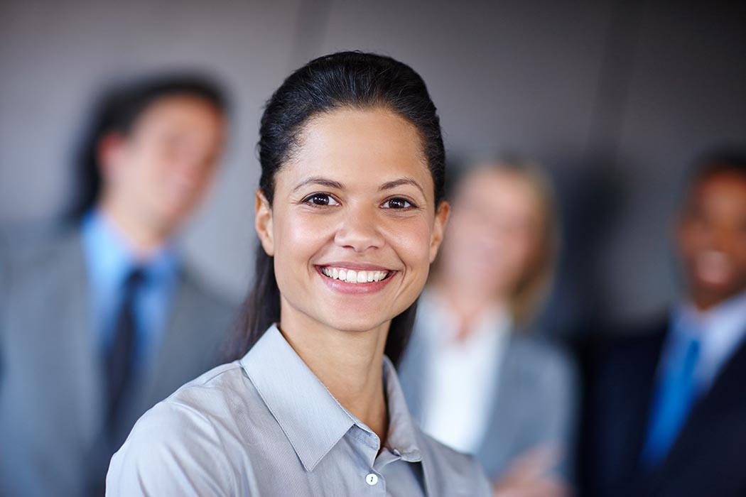 Smiling person with blurry co-workers in the background